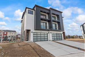 Contemporary house with board and batten siding, an attached garage, a balcony, and concrete driveway