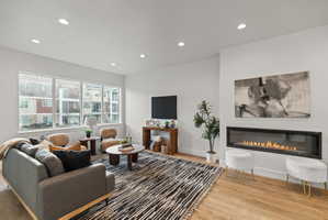 Living room featuring a glass covered fireplace, recessed lighting, and light wood-type flooring
