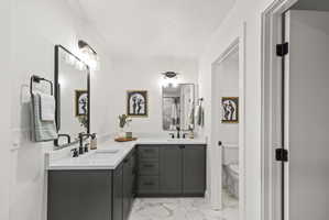 Bathroom with double vanity, light marble finish flooring, and a shower stall