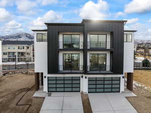 Modern home featuring a mountain view, driveway, a garage, and a balcony