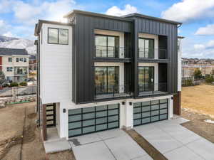 View of front of house with board and batten siding, a garage, a balcony, concrete driveway, and a mountain view