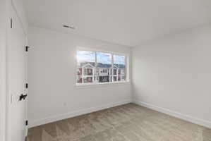 Spare room featuring light carpet and baseboards