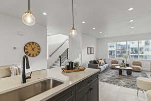 Kitchen featuring light stone counters, open floor plan, hanging light fixtures, and light wood-style flooring