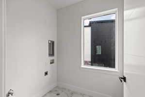 Laundry area with hookup for a washing machine, electric dryer hookup, and light marble finish flooring