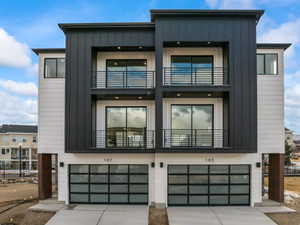 Modern home featuring a garage, board and batten siding, concrete driveway, and a balcony