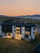 Back of house at dusk with a patio area, a yard, board and batten siding, and a mountain view