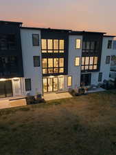 Back of house featuring a lawn, a patio, and board and batten siding