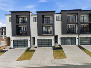 Modern home with board and batten siding, a garage, concrete driveway, and a balcony