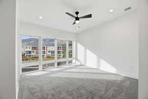 Empty room featuring light carpet, ceiling fan, recessed lighting, and a mountain view