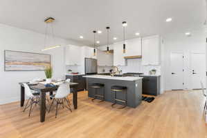 Modern kitchen and dining area featuring light wood-finish flooring