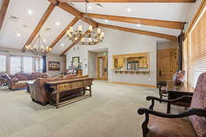 Living area with suspended lighting and light colored carpet