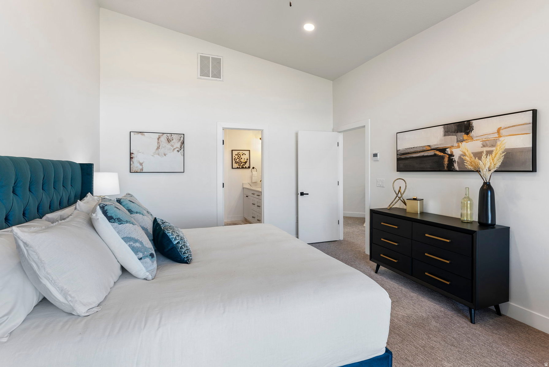 Spacious bedroom featuring high vaulted ceilings, light-toned carpeting, and white walls