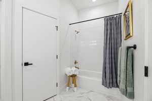 Full bath featuring shower / tub combo, recessed lighting, and light marble finish flooring
