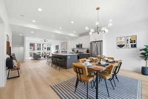 Dining room with light wood-style flooring, ceiling fan, and hanging lights
