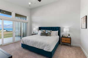 Expansive room featuring a wall of sliding glass doors, transom windows, a high ceiling, recessed lighting, and soft carpet flooring
