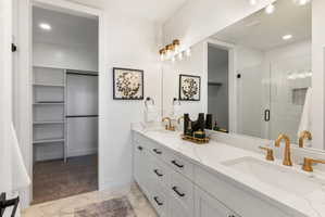 Bathroom featuring a double vanity with white cabinetry and gold-finish fixtures