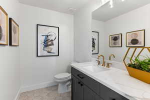 Vanity featuring a white countertop with integrated sink, gold-tone faucet, and dark cabinetry
