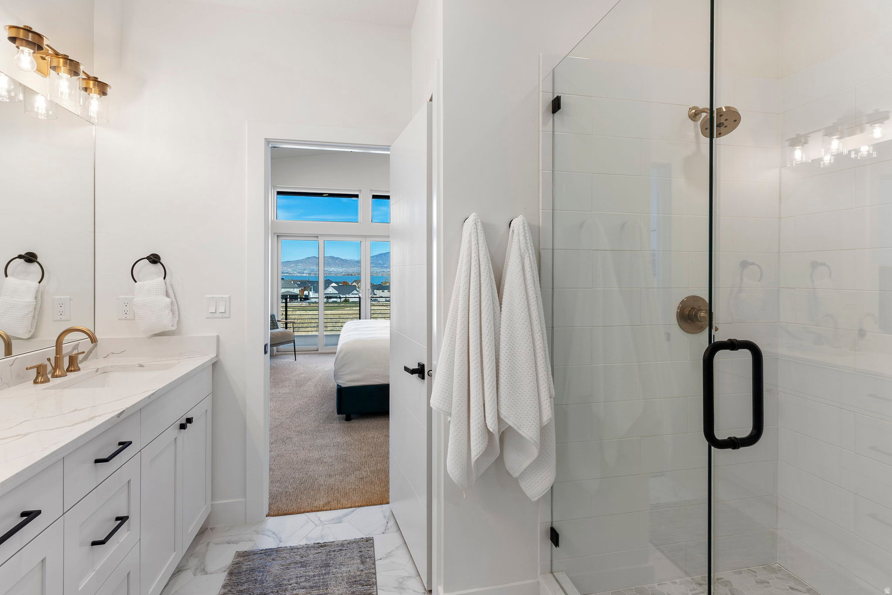 Modern bathroom featuring a glass-enclosed shower with a brushed brass shower head and black hardware