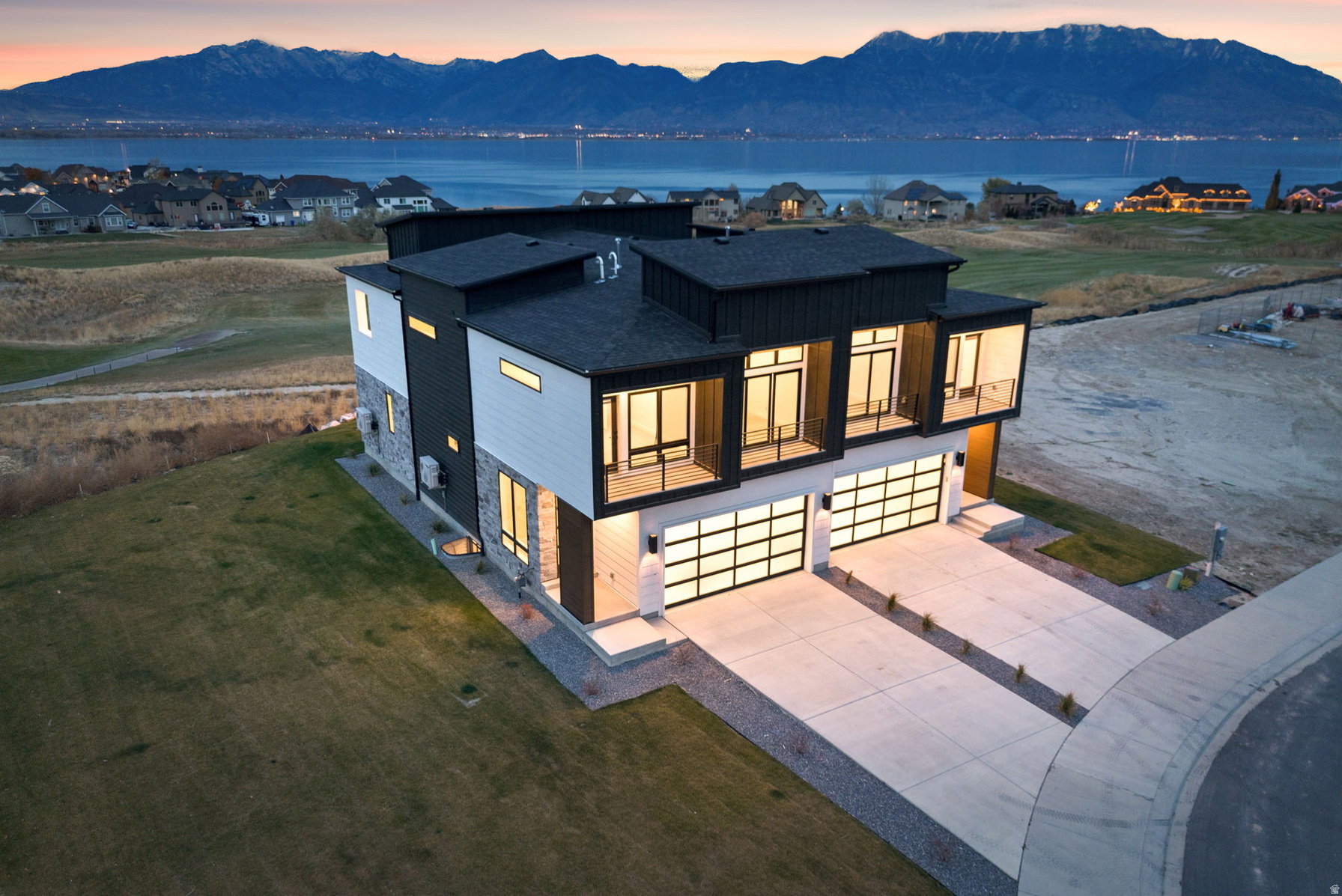 Modern architectural design featuring expansive glass garage doors, multiple balconies, and a distinctive dark and light exterior facade
