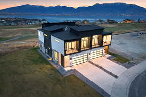 Modern architectural design featuring expansive glass garage doors, multiple balconies, and a distinctive dark and light exterior facade