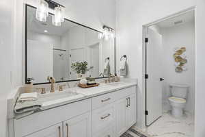Bathroom with double vanity, light marble finish flooring, and a shower stall