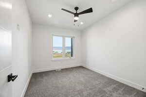 Unfurnished room with dark colored carpet, a ceiling fan, a water view, and recessed lighting