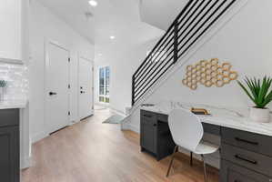 Integrated workspace featuring dark cabinetry with matte black hardware, a light-toned countertop, and wood-finish flooring