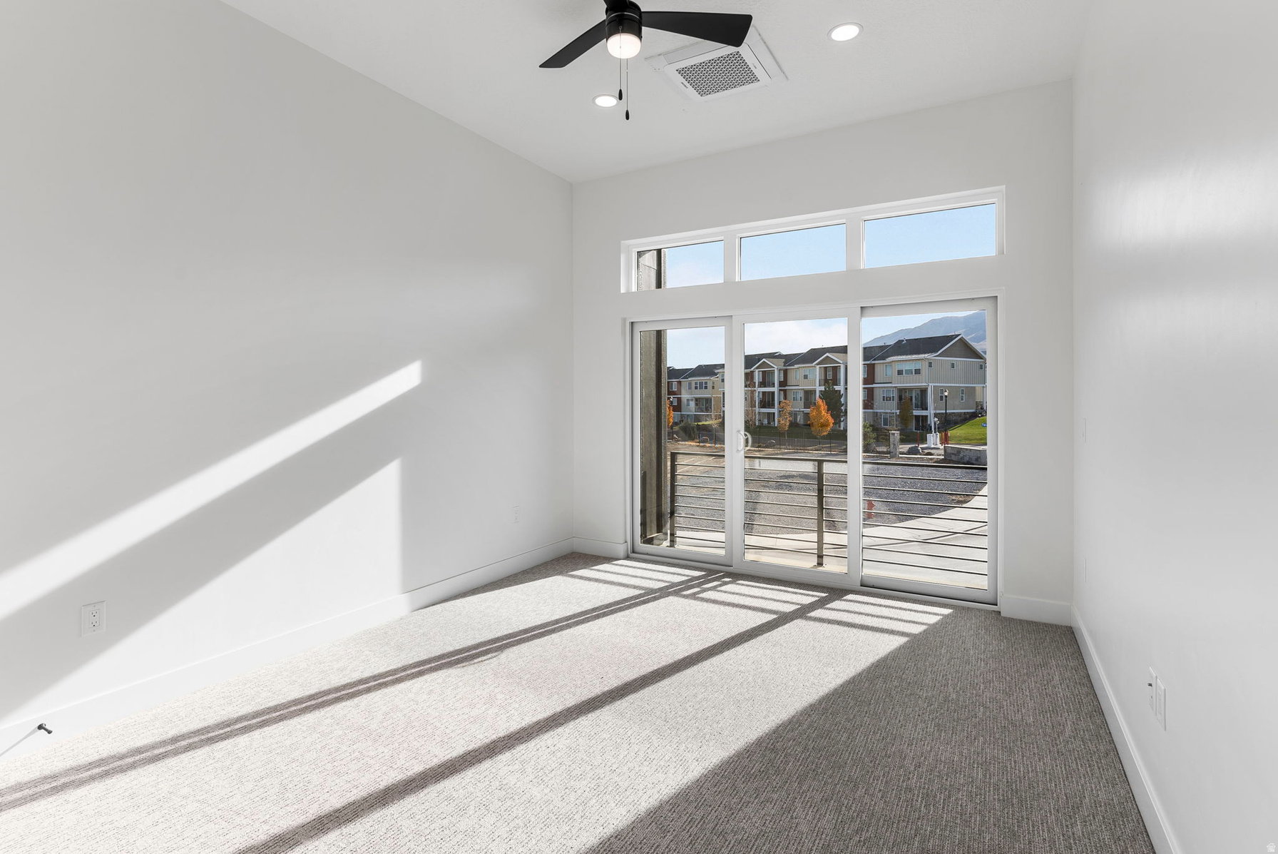 Room featuring a full glass sliding door, upper transom windows, recessed lighting, and a ceiling fan