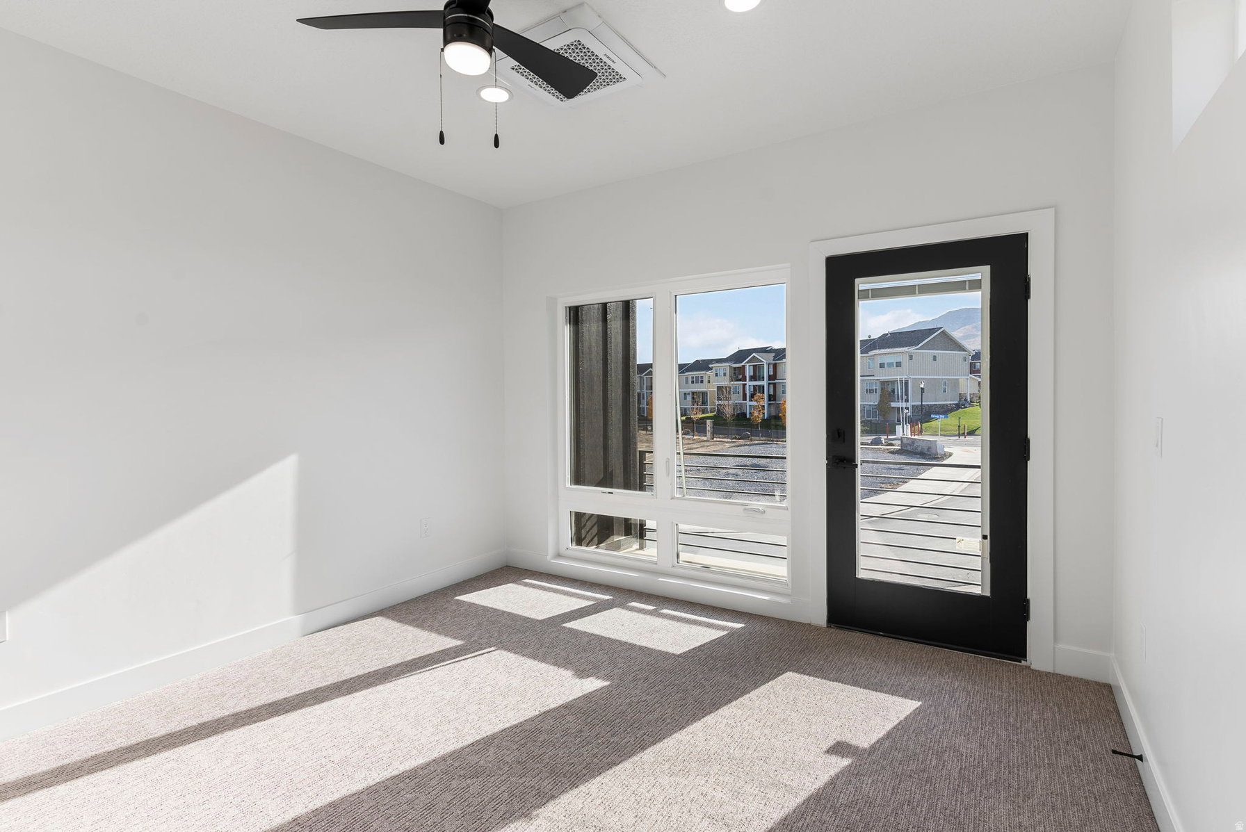 Bright room featuring a black ceiling fan, recessed lighting, white walls, and neutral carpeting