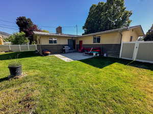 Rear view of property with brick siding, a fenced backyard, a gate, and stucco siding
