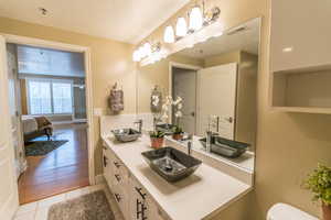 Bathroom with a textured ceiling, double vanity, and light tile patterned flooring