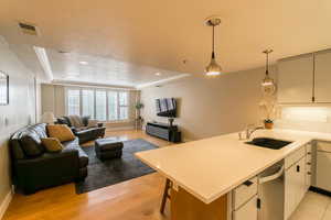 Kitchen with open floor plan, a tray ceiling, a peninsula, light wood-style flooring, and decorative light fixtures