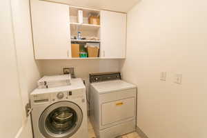 Laundry area featuring washer and dryer, cabinet space, and light tile patterned floors