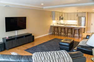 Living room featuring light wood-type flooring, crown molding, and recessed lighting