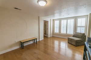 Sitting room with a textured ceiling and light wood finished floors