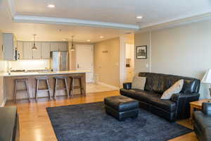 Living area with light wood-type flooring, ornamental molding, recessed lighting, and a textured ceiling