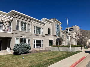 Front view of property with stucco siding, a yard, and a balcony