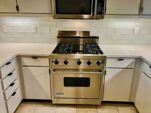 Kitchen with Viking Gas Range , light stone counters, and decorative backsplash