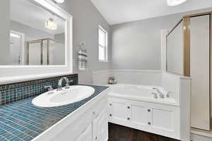 Bathroom with vanity, a stall shower, a garden tub, and dark wood-type flooring