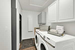Laundry area featuring independent washer and dryer, cabinet space, and dark wood-style floors