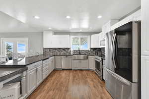 Kitchen featuring stainless steel appliances, tasteful backsplash, white cabinetry, a peninsula, and recessed lighting