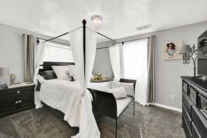 Bedroom featuring dark carpet and a textured ceiling