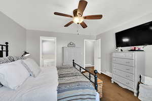 Bedroom featuring ensuite bathroom, dark colored carpet, ceiling fan, and a textured ceiling