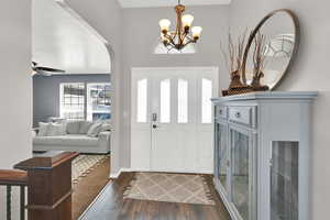 Foyer featuring dark wood-style flooring, arched walkways, ceiling fan, and hanging lights