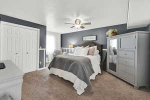 Bedroom with a closet, dark colored carpet, ceiling fan, and a textured ceiling