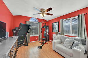 Exercise room with light wood-type flooring, healthy amount of natural light, a textured ceiling, and a ceiling fan