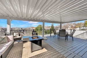 Wooden deck featuring an outdoor living / dining area, an outdoor fire pit, a residential view, and a patio