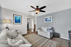 Living room featuring dark carpet, ceiling fan, arched walkways, a fireplace, and hanging lights