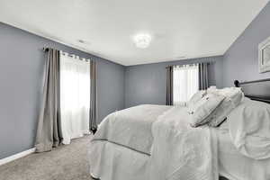 Bedroom featuring light colored carpet and a textured ceiling