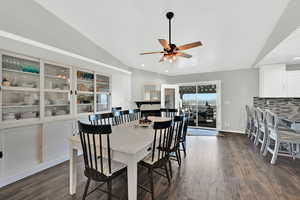 Dining space with dark wood-style floors, ceiling fan, and vaulted ceiling